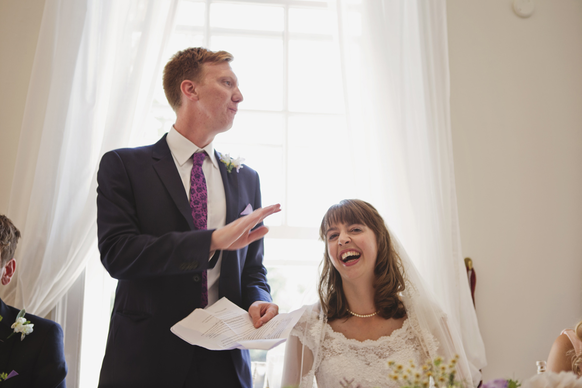 A bride laughs as her husband gives his wedding speech