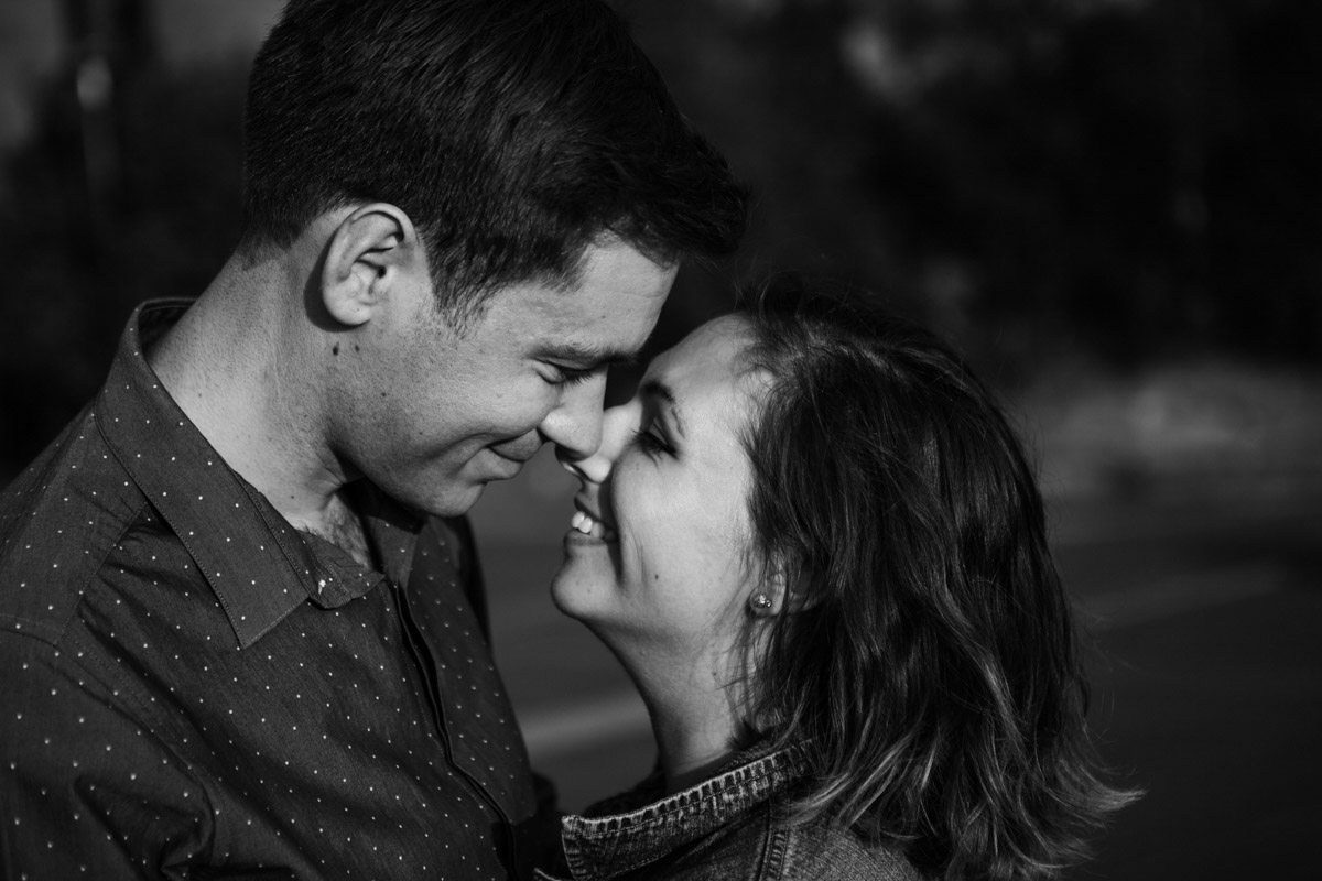 A black & white image of newly engaged couple facing each other smiling